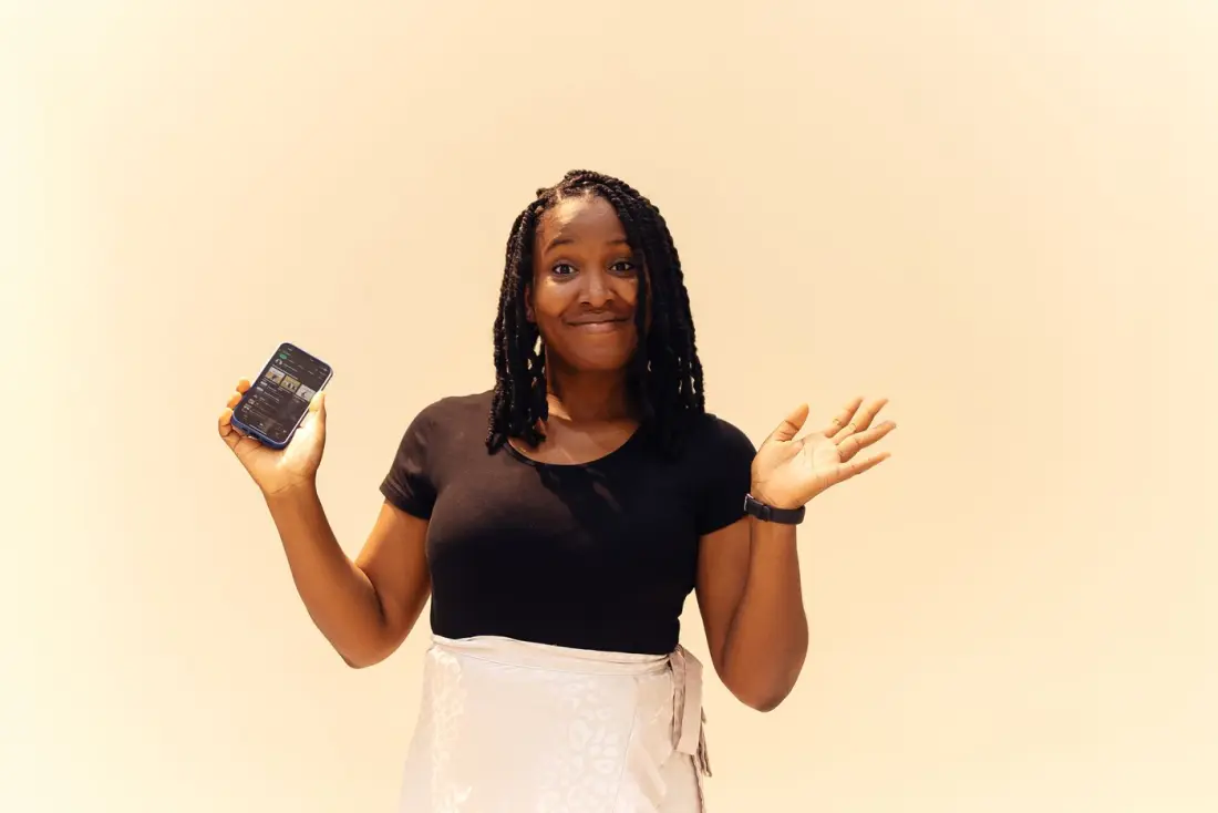 A creator holding up her phone with a playful shrug