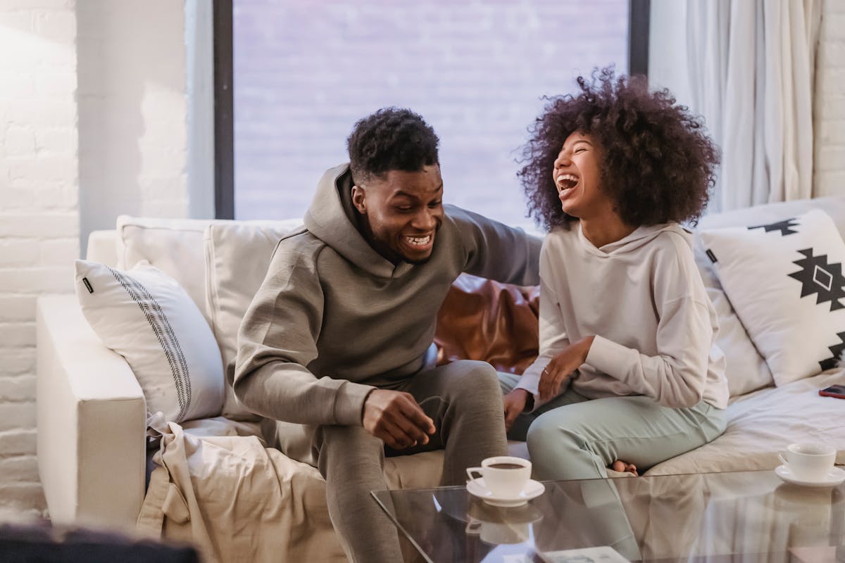 Two flatmates laughing together on their sofa