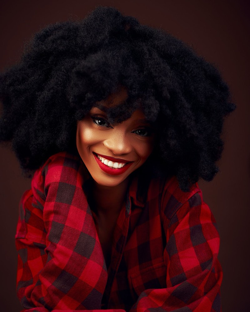 A creator with a big afro and a red flannel shirt, grinning at the camera